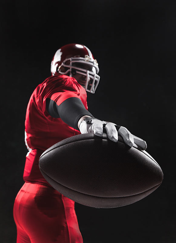 Photo of football player holding a ball outward